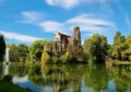 brown concrete building beside green trees and body of water during daytime